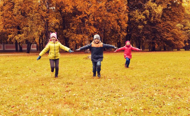 秋、子供時代、レジャー、人のコンセプト – 屋外で飛行機を走らせたり遊んだりする幸せな小さな子供たちのグループ