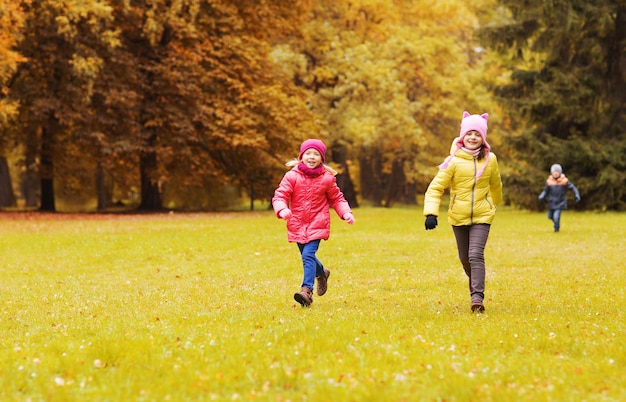 autumn, childhood, leisure and people concept - group of happy little kids playing tag game and running in park outdoors