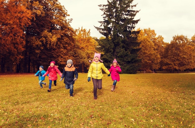 Photo autumn, childhood, leisure and people concept - group of happy little kids playing tag game and running in park outdoors