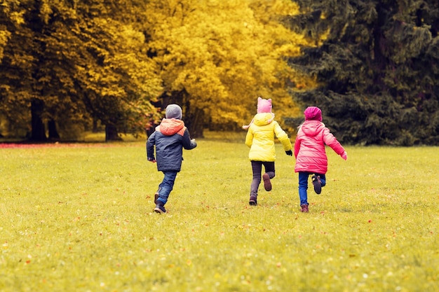 가을, 어린 시절, 여가, 그리고 사람들의 개념 - 태그 게임을 하고 야외 공원에서 뛰는 행복한 어린 아이들