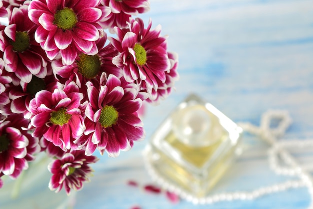 Autumn colors of chrysanthemum and perfume on a blue wooden table