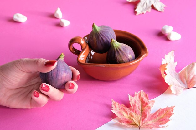 Autumn colors Purple and magenta fig fruits in terracotta bowl in hand