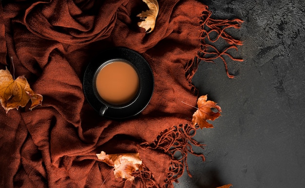 Autumn composition. Brown scarf, coffee with milk, dark chocolate with almonds and autumn maple leaves. Flat lay. Top view. High quality photo