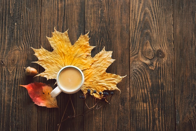 Autumn composition Cup of coffee and autumn dried leaves on wood background Flat lay top view