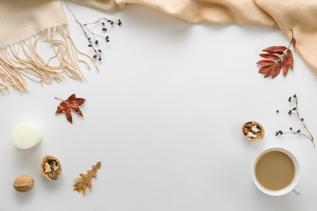 Autumn composition. Cup of coffee, plaid, candle, dried leaves on white