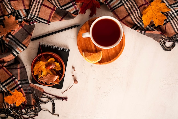 Autumn composition. A cup of tea, scarf, autumn leaves, glasses, notepad, pencil. Flat lay, top view, copy space. High quality photo