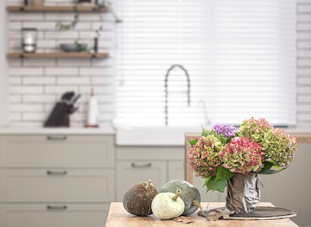 Autumn composition of flowers of hydrangeas and pumpkins on the space of the interior of a modern kitchen.