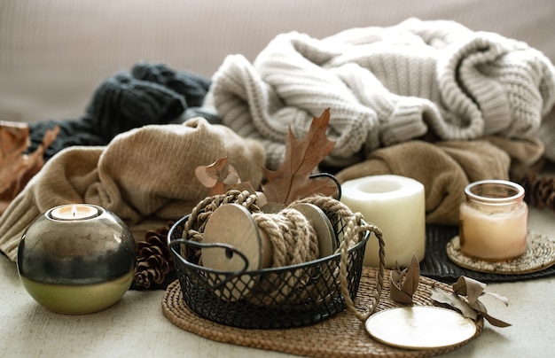 Autumn composition of home decor details, candles, rope and warm clothes on the background. Home comfort, autumn atmosphere