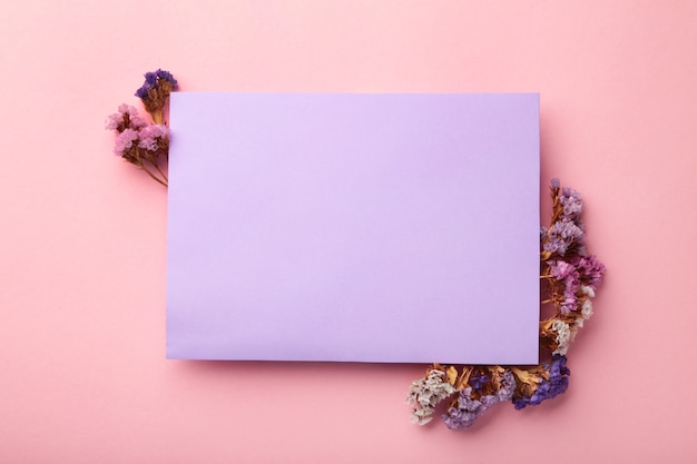 秋の構成。紫色の背景にドライフラワーと葉で空白の紙。秋、秋のコンセプト。フラットレイ、上面図、コピースペース、正方形