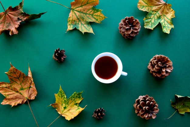 Autumn composition. Pattern made of october dried leaves, pine cones and tea cup background. Template autumn, fall, halloween, harvest thanksgiving concept. Flat lay, top view, copy space background