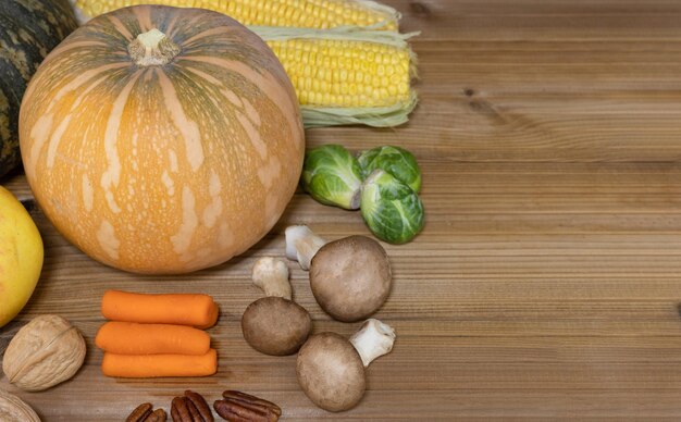 Autumn composition Pumpkins corn walnuts on wooden table Copy space