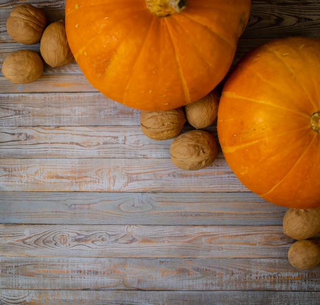 Autumn composition of pumpkins and nuts on a wooden background Place for your text