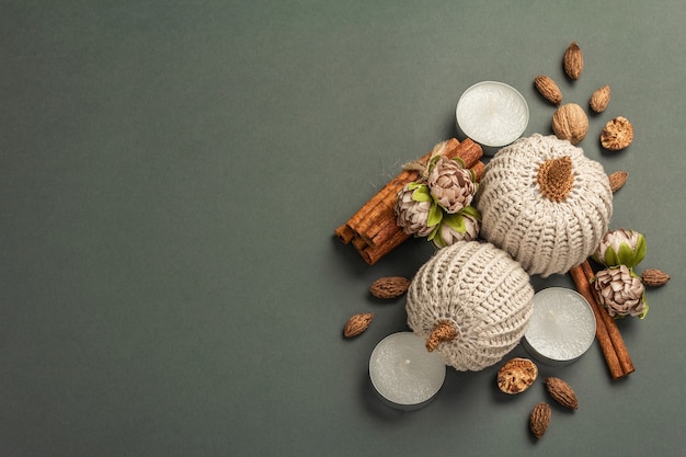 Autumn composition with crocheted pumpkins, candles, spices, and traditional decor. A trendy dark gray background, top view