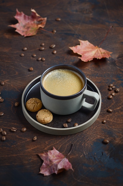 Composizione autunnale con tazza di caffè e foglie di autunno sul tavolo di legno scuro