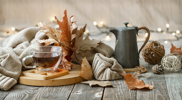 Autumn composition with a cup of tea and decorative details of home comfort.