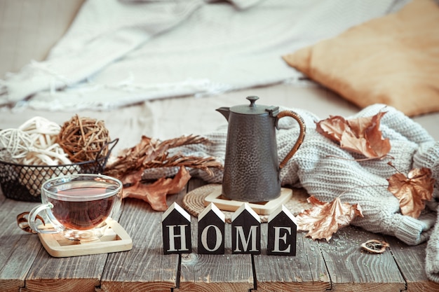 Photo autumn composition with a cup of tea and wooden word home.