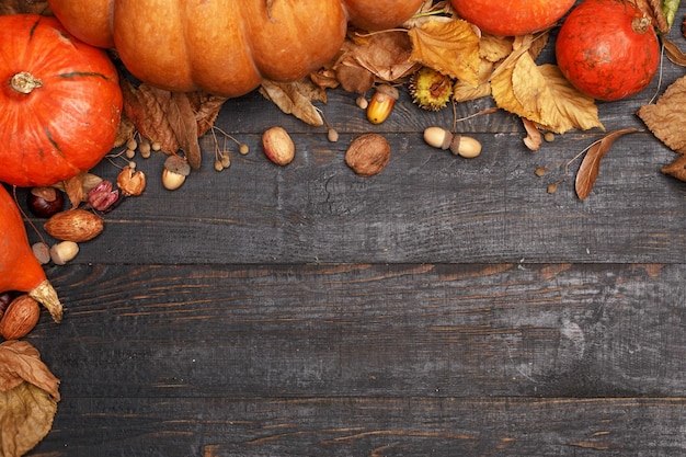 Autumn composition with dry leaves and ripe pumpkins on a dark wooden table Top view Copy space