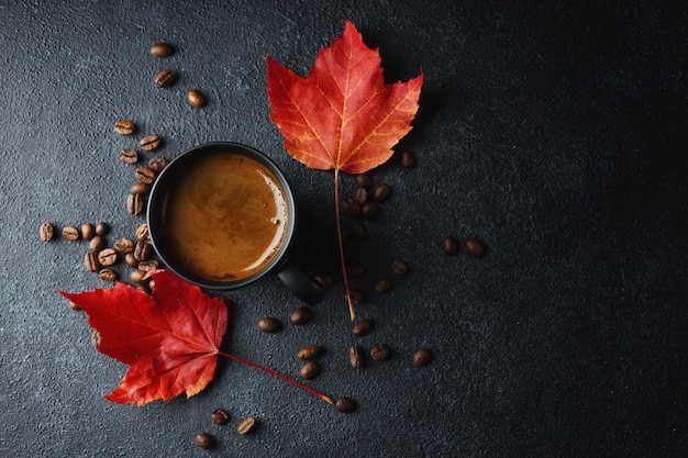 カップとカエデの葉に淹れたてのコーヒーと秋の構成