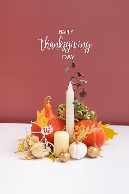 Autumn composition with Happy Thanksgiving Day greeting text Dried leaves pumpkins and candles on white pink background