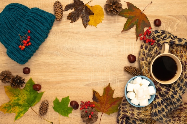 Autumn composition with hat, leaves and marshmallows. Shot from above on a wooden background. Place for your text.