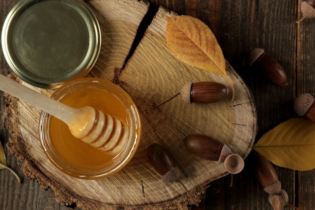 Autumn composition with honey acorns and yellow leaves on a wooden stand on a brown wooden table. top view