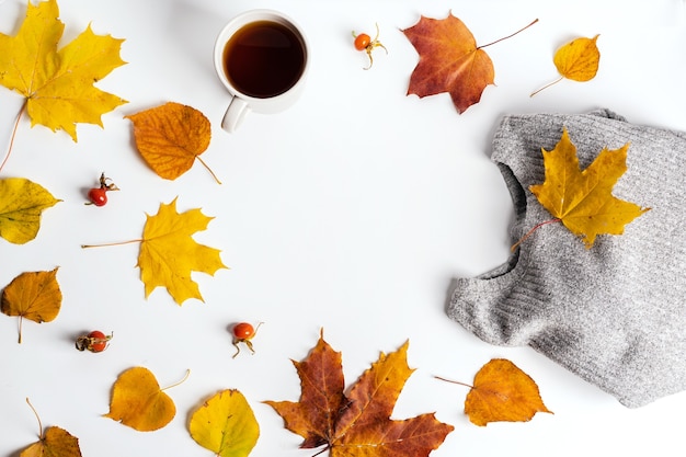 Autumn composition with maple leaves, a sweater and a mug of tea