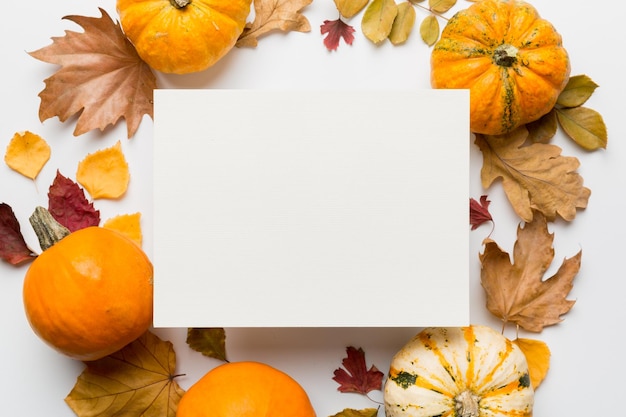 Autumn composition with paper blank and dried leaves with pumpkin on table Flat lay top view copy space