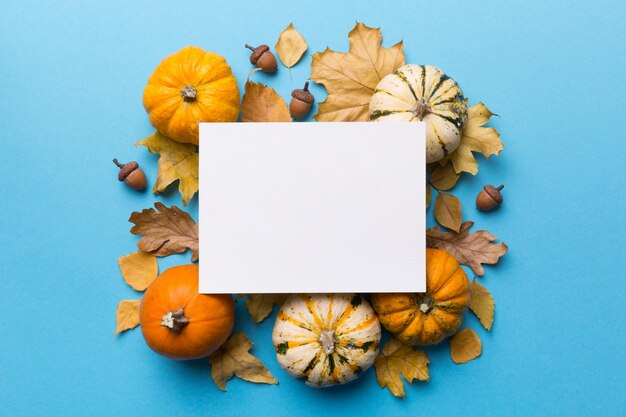 Autumn composition with paper blank and dried leaves with pumpkin on table Flat lay top view copy space