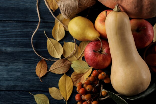 Autumn composition with pumpkin and autumn fruits with apples and pears and yellow leaves on a dark blue table. top view