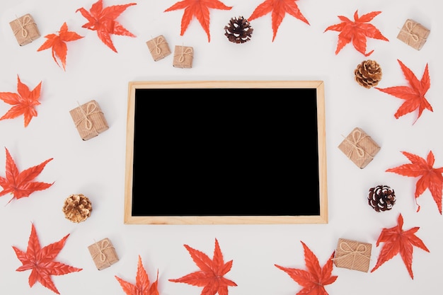 白地にカラフルなカエデの葉で飾られた秋の組成木製表面黒板