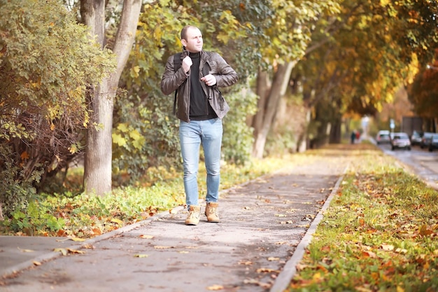 Autumn concept A man walks through the city Autumn leaves on the footpath