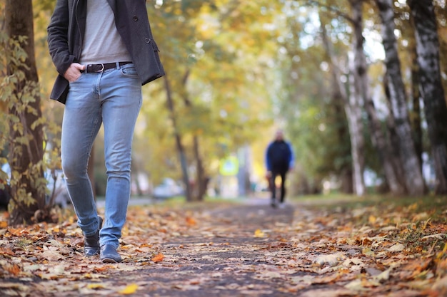 Foto concetto di autunno. piedi dei pedoni sulla strada. foglie d'autunno sul sentiero.