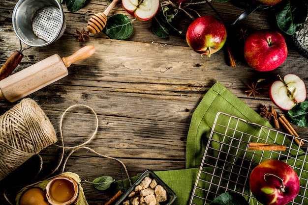 Autumn cooking background, Apple pie baking concept, fresh red apples, sweet spices, sugar, flour, rolling pin, eggs, baking utensils, wooden background