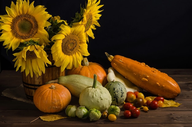 Cornucopia d'autunno. natura morta con girasoli di verdure su una superficie nera con spazio di copia. ringraziamento e raccolto.