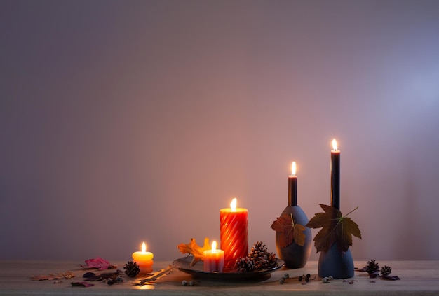 Autumn dark decor with candles on wooden shelf on background wall