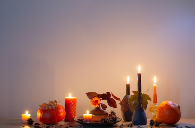 Autumn dark decor with candles on wooden shelf on background wall