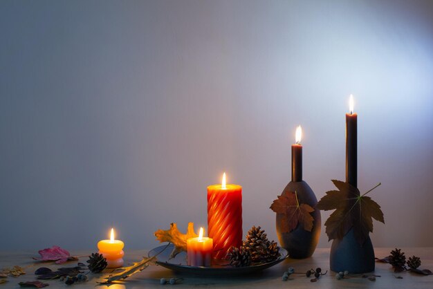 Autumn dark decor with candles on wooden shelf on background wall