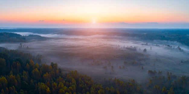 Autumn dawn over foggy forest and river aerial drone view