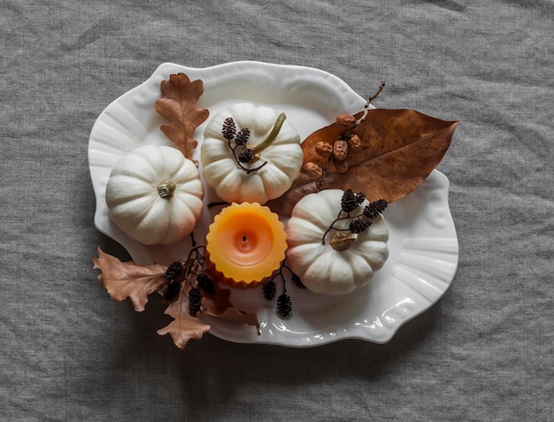 Autumn decor for the table serving interior decorative small pumpkins leaves cones candle in a vintage plate