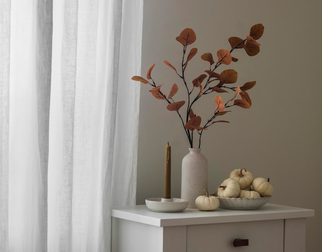 스칸디나비아 스타일의 거실에 있는 흰색 나무 서랍장의 가을 장식