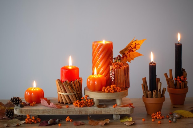 autumn decor with burning candles on wooden shelf