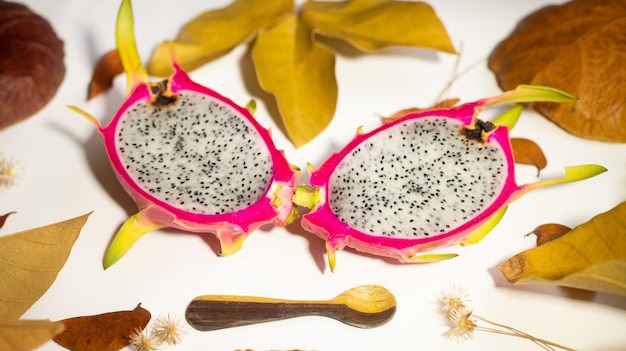 붉은 피부와 흰색 펄프가 있는 가을 용 과일 PITAHAYA, 마른 잎이 있는 흰색 배경