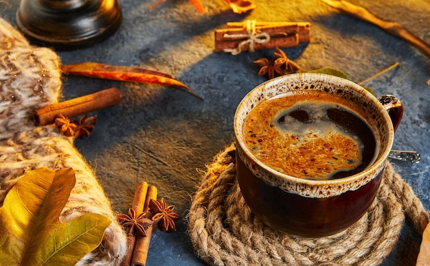 Autumn, fall leaves, a hot steaming cup of coffee and a warm scarf against the background