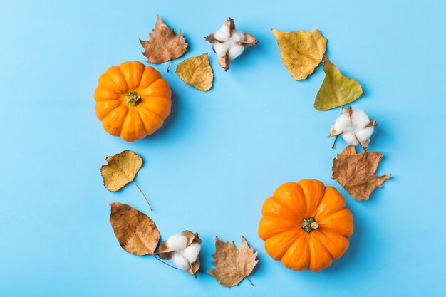 가을 추수 감사절에는 장식용 오렌지 호박과 말린 잎이 있습니다. 평면도, 평면도, 복사 공간, 인사말 카드의 정물 배경