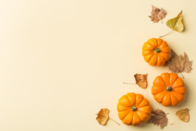 Composizione del giorno del ringraziamento autunnale con zucche arancioni decorative e foglie secche. disposizione piana, vista dall'alto, copia spazio, sfondo giallo natura morta per biglietto di auguri