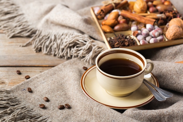 가을, 가을, 겨울 가정 장식은 스칸디나비아, 휘게 스타일입니다. 커피 한 잔, 따뜻한 모직 스카프, 소박한 나무 테이블에 부드러운 격자 무늬가 있는 계절 구성.