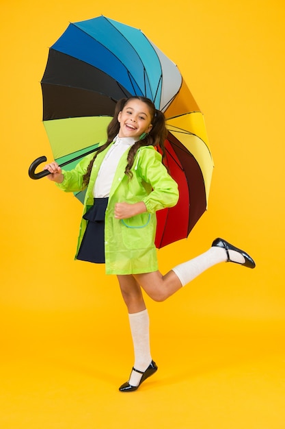 Autumn fashion for kids. small girl feel comfortable under umbrella. happy child with colorful umbrella. cheerful school girl in trendy raincoat. ready for autumn rainy weather.