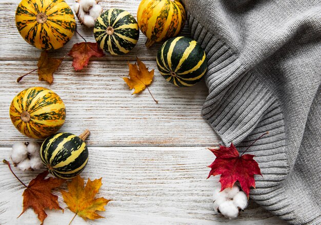 Autumn flat lay of leaves, pumpkins and grey scarf