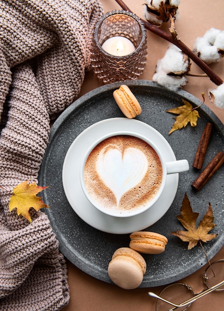 autumn flat lay with  cup of coffee, warm blanket, decorative striped pumpkins ,candles and autumn leaves