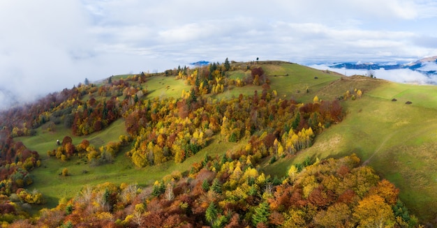 Autumn flight through blue sky in Carpatian autumn mountains, Aerial panoramic drone shot